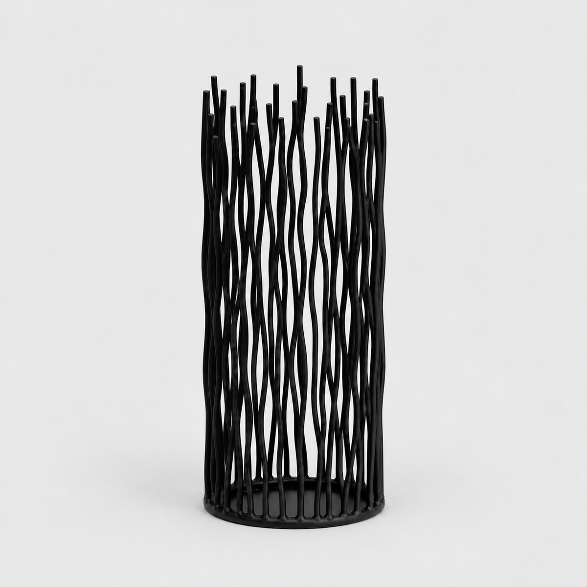 Medium black iron pillar candle holder with wavy vertical rods on a light gray background