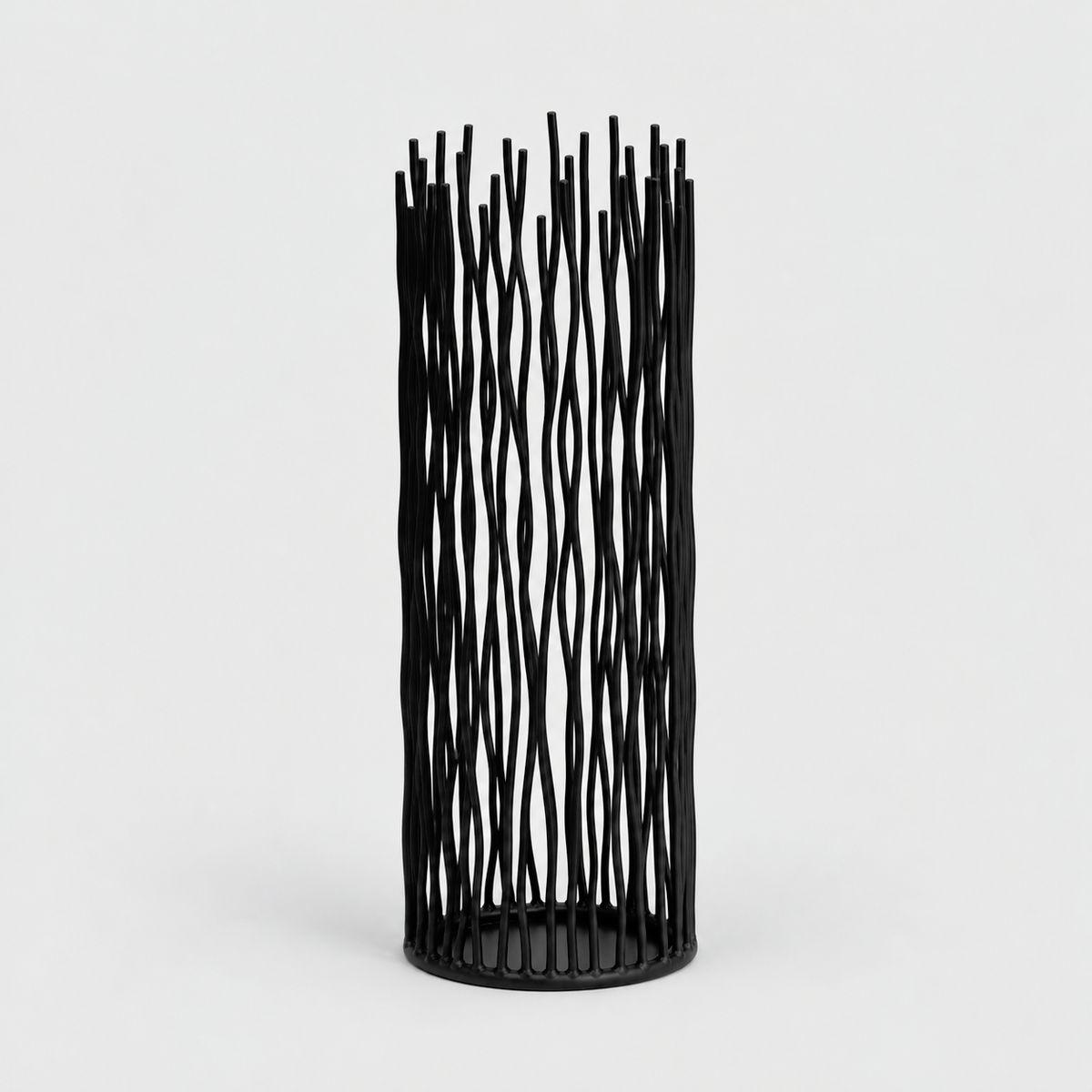 Large black iron pillar candle holder with wavy vertical rods on a light gray background