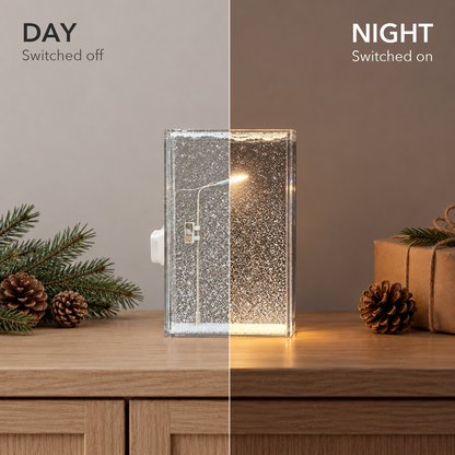 The same snowfall night light on an oak sideboard, switched off in daylight on the left and lit warm in the evening on the right