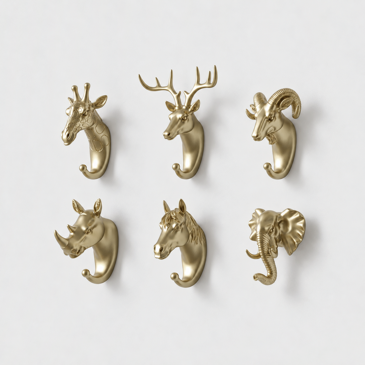 Six gold animal head wall hooks, giraffe, deer, ram, rhino, horse and elephant, on a plain light gray wall