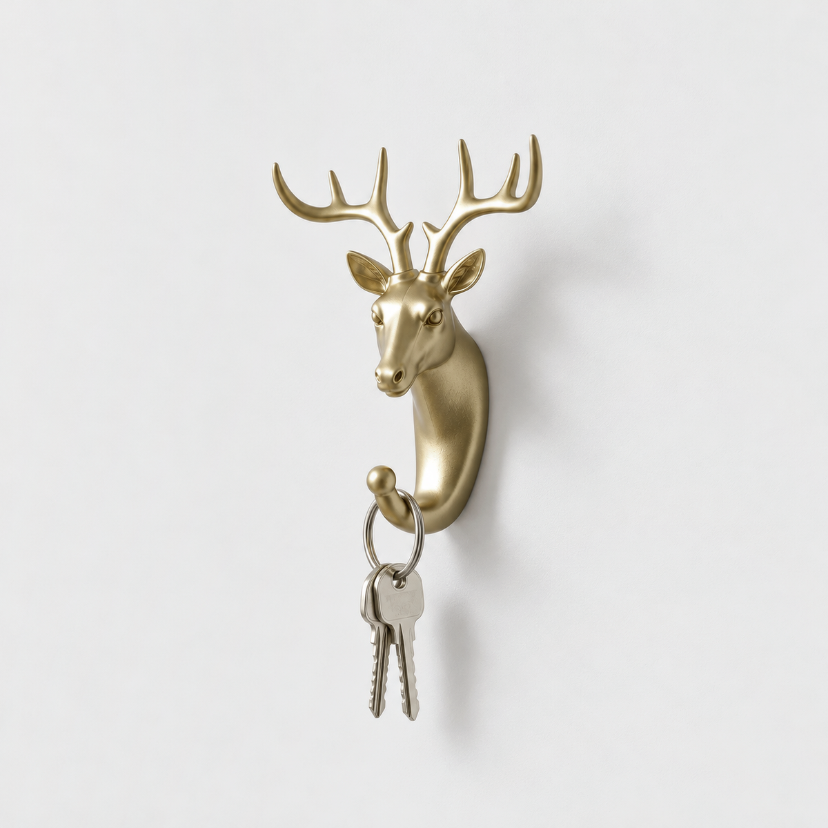 Close-up of a gold deer head wall hook with a key ring hanging in its curled hook