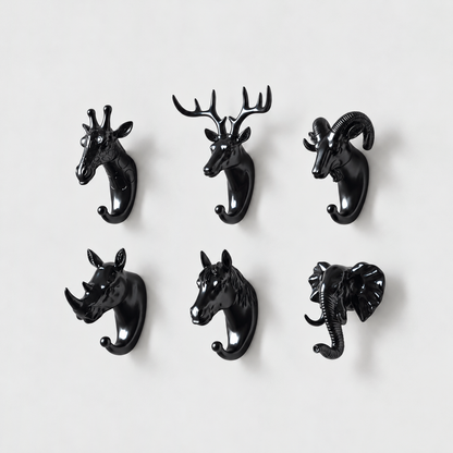 Six black animal head wall hooks, giraffe, deer, ram, rhino, horse and elephant, on a plain light gray wall