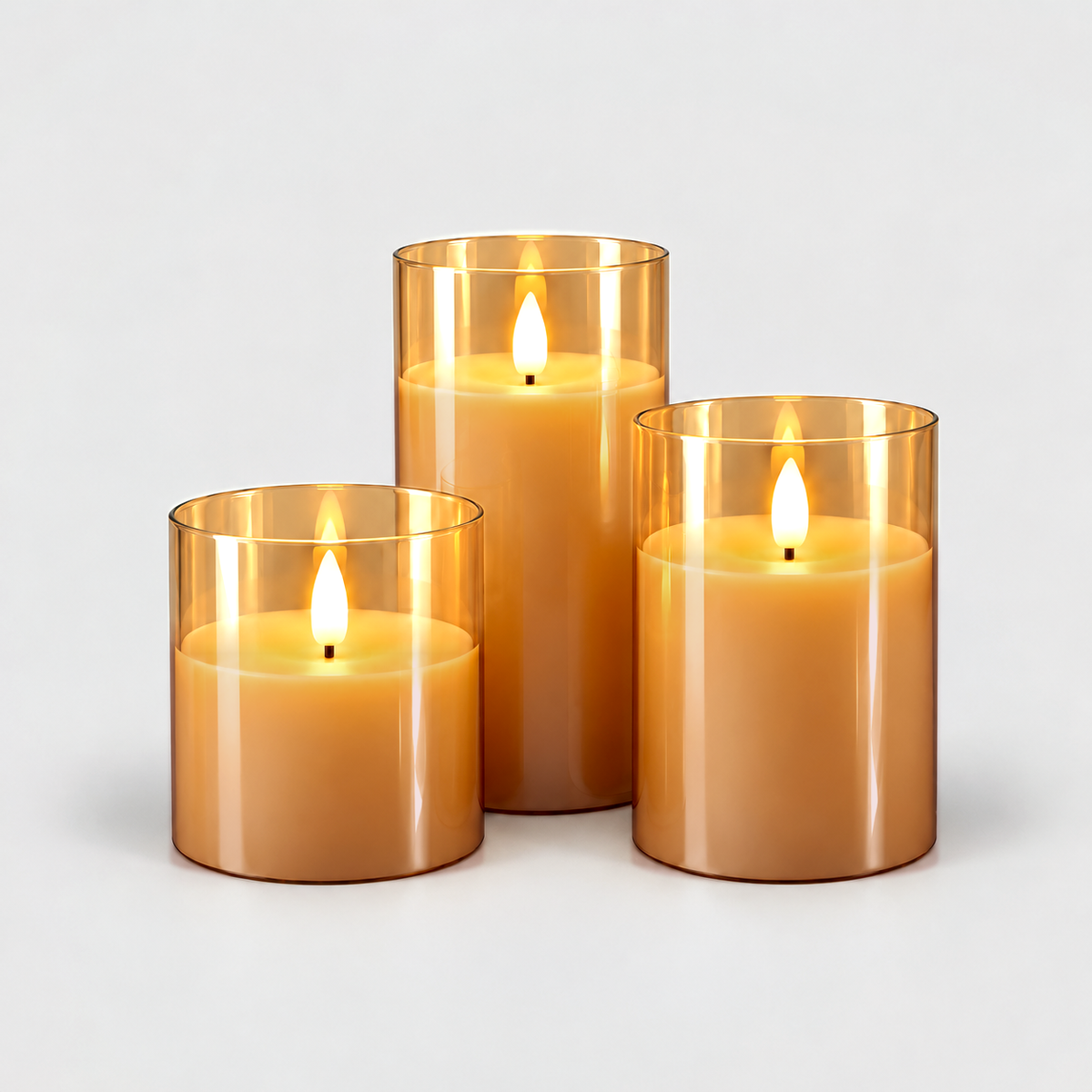 Three flameless LED pillar candles in amber glass sleeves, lit, in three heights