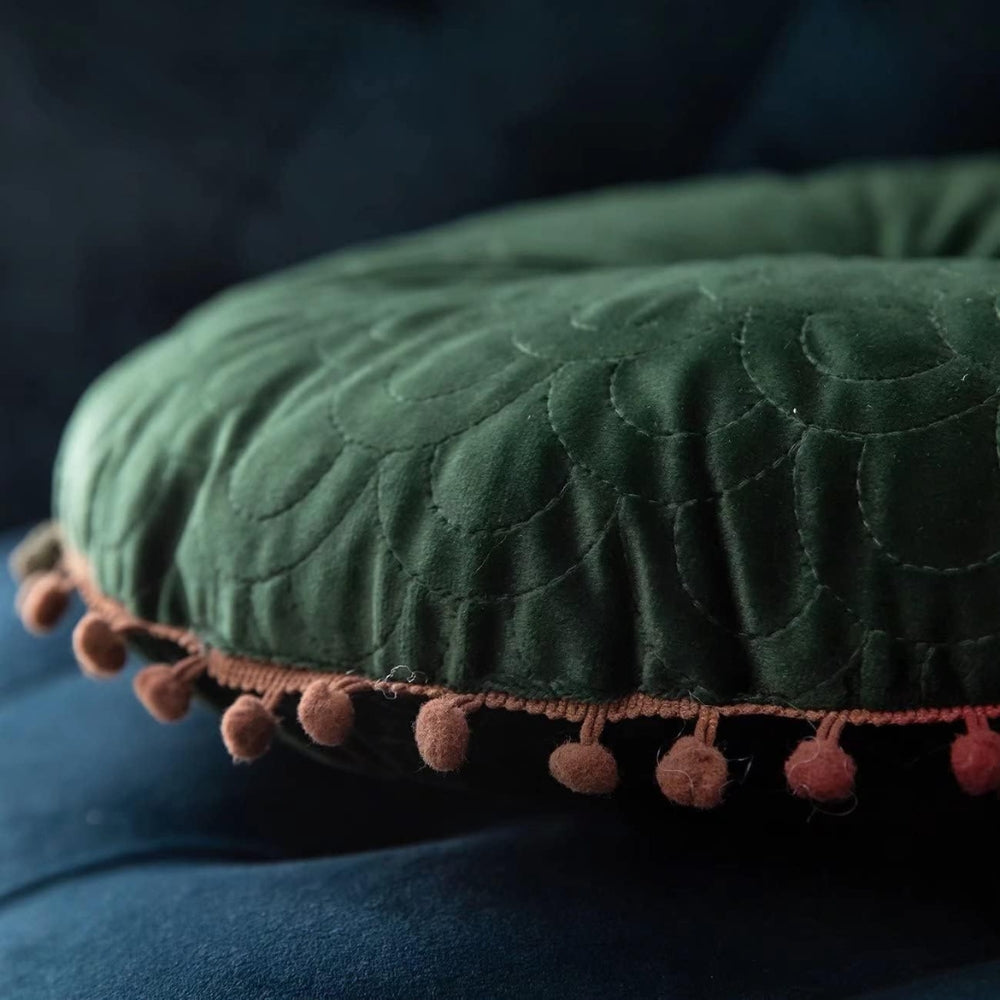Side close-up of the green cushion showing its thickness and pom-pom trim
