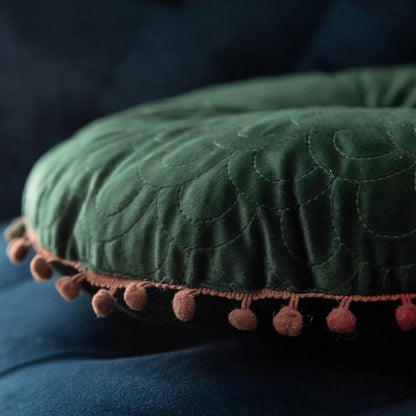 Side close-up of the green cushion showing its thickness and pom-pom trim