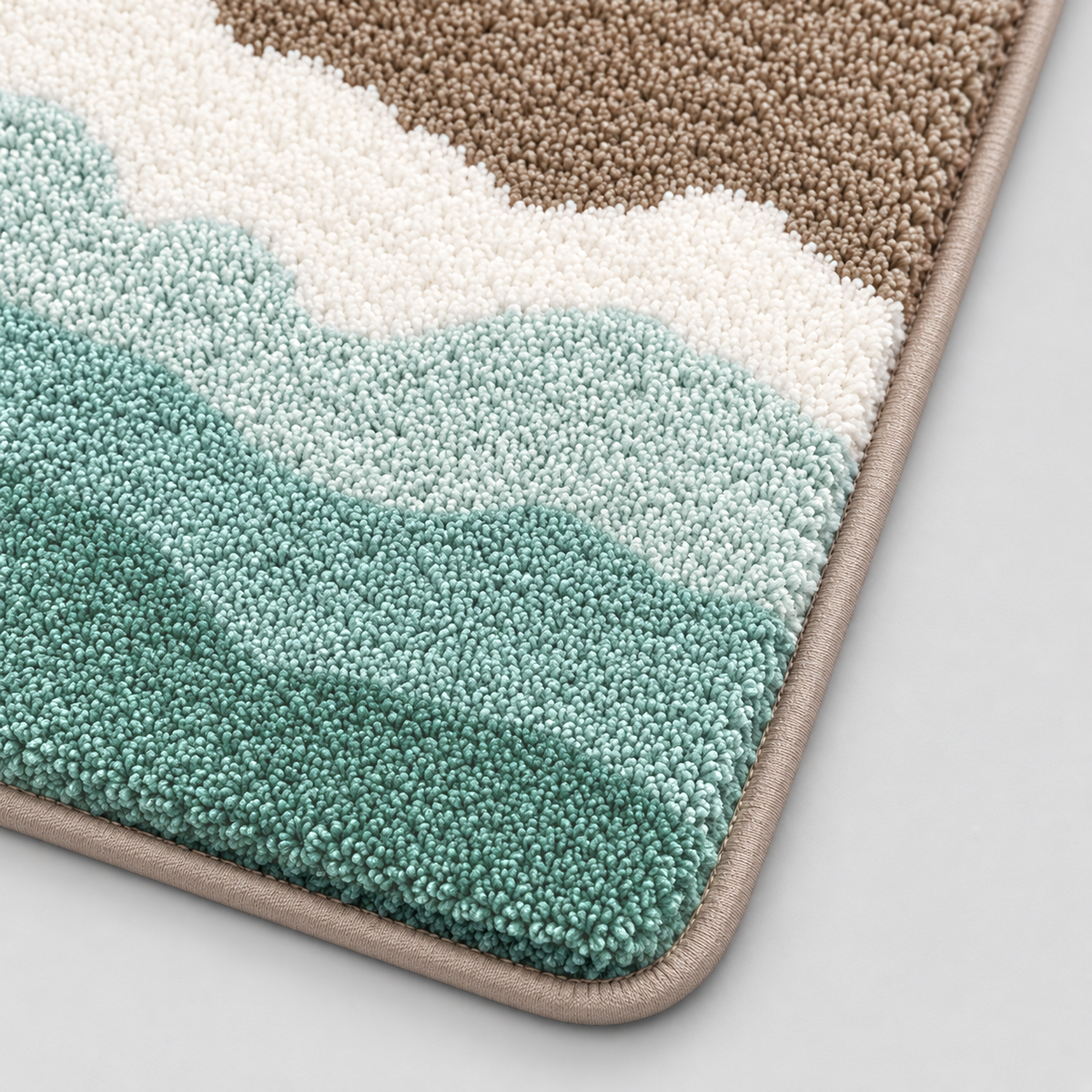 Close-up of the sand bath mat's soft tufted pile, white wave crest and rounded bound corner