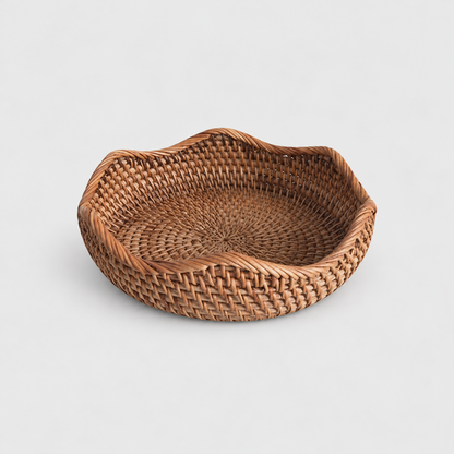 Small shallow round rattan basket with a wavy rope-wrapped rim on a light gray background