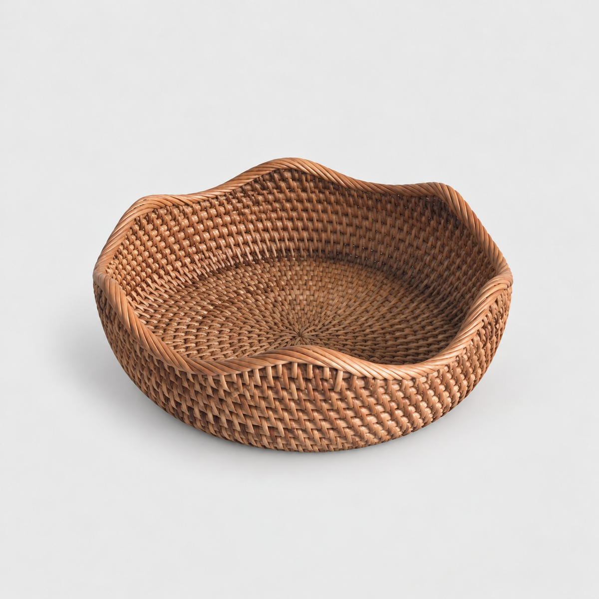 Medium shallow round rattan basket with a wavy rope-wrapped rim on a light gray background