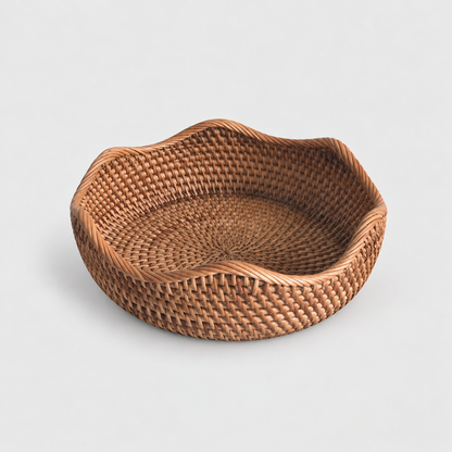 Medium shallow round rattan basket with a wavy rope-wrapped rim on a light gray background
