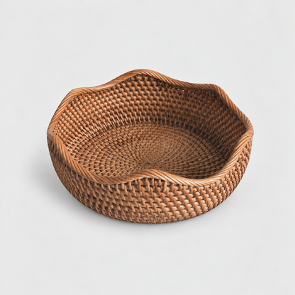 Large shallow round rattan basket with a wavy rope-wrapped rim on a light gray background