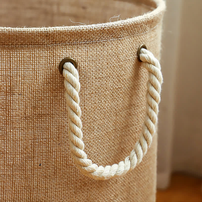 Close-up of a twisted cream rope handle threaded through dark metal eyelets on the linen weave