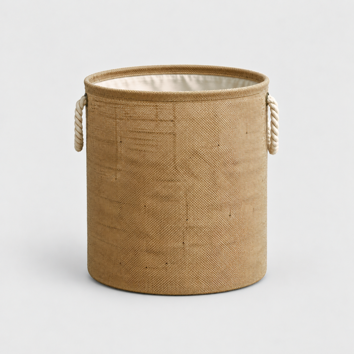Large round cotton linen laundry basket in natural tan with two rope handles, on a light gray background