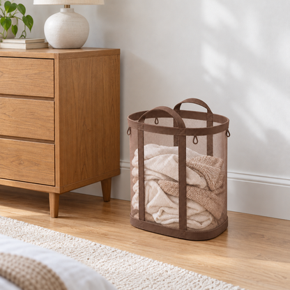 Brown mesh laundry basket with laundry inside next to an oak dresser