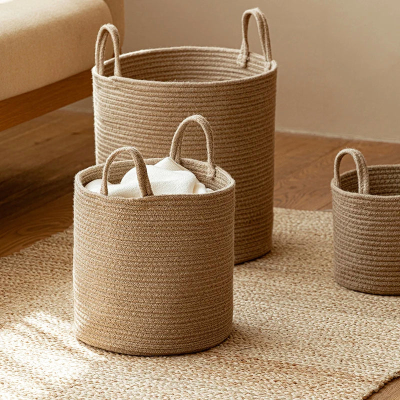 Tan cotton rope baskets on a jute rug in sunlight, a folded white towel in the front basket
