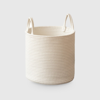 Medium round white cotton rope storage basket with two upright rope loop handles, on a light gray studio background