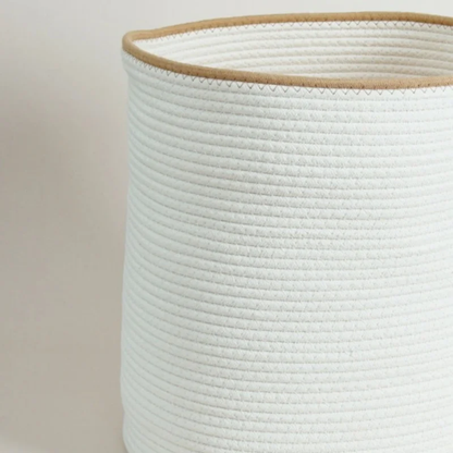 Close-up of the white rope basket's tan rim and zigzag stitch above rows of coiled white cotton rope