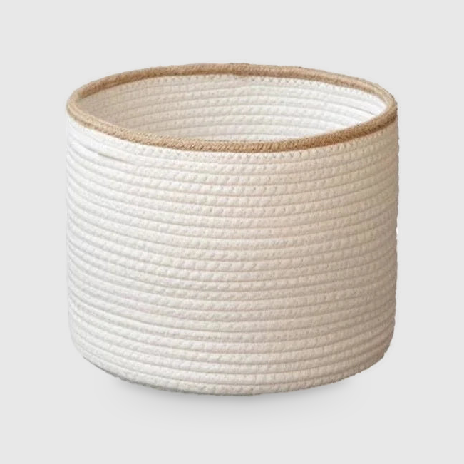 Small round white cotton rope basket with a beige braided rim, on a light gray background