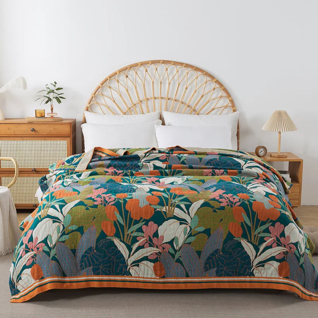 Teal floral cotton coverlet with orange flowers and an orange striped border spread over a bed