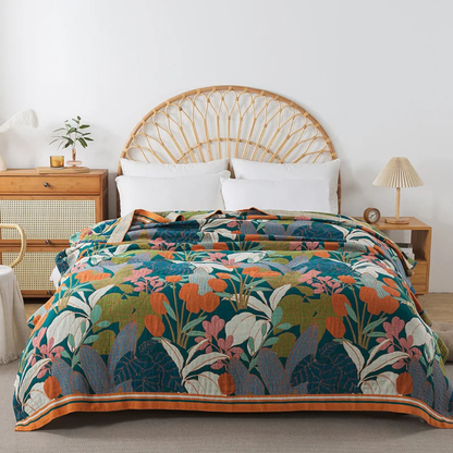 Teal floral cotton coverlet with orange flowers and an orange striped border spread over a bed