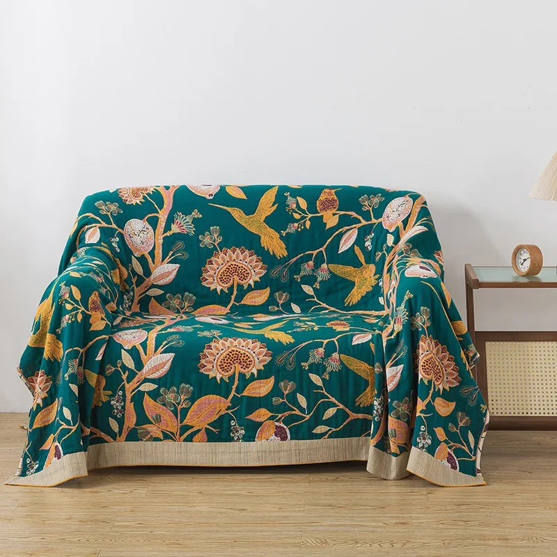 Floral cotton coverlet with a teal face draped over a loveseat as a sofa cover