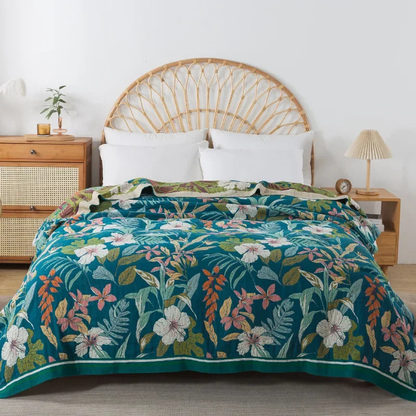 Deep teal floral cotton coverlet with white and pink flowers spread over a bed