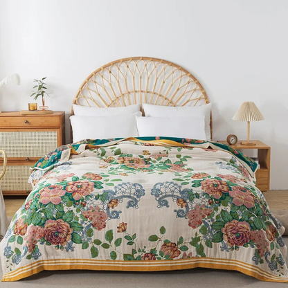 Cream floral cotton coverlet with pink flowers and blue lace motifs spread over a bed