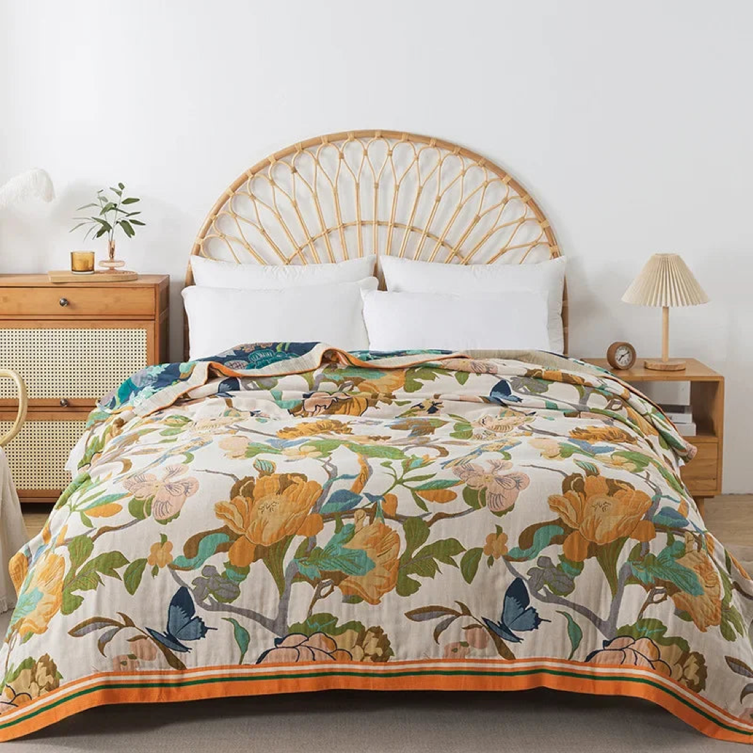 Cream cotton coverlet with golden mustard flowers and blue butterflies spread over a bed