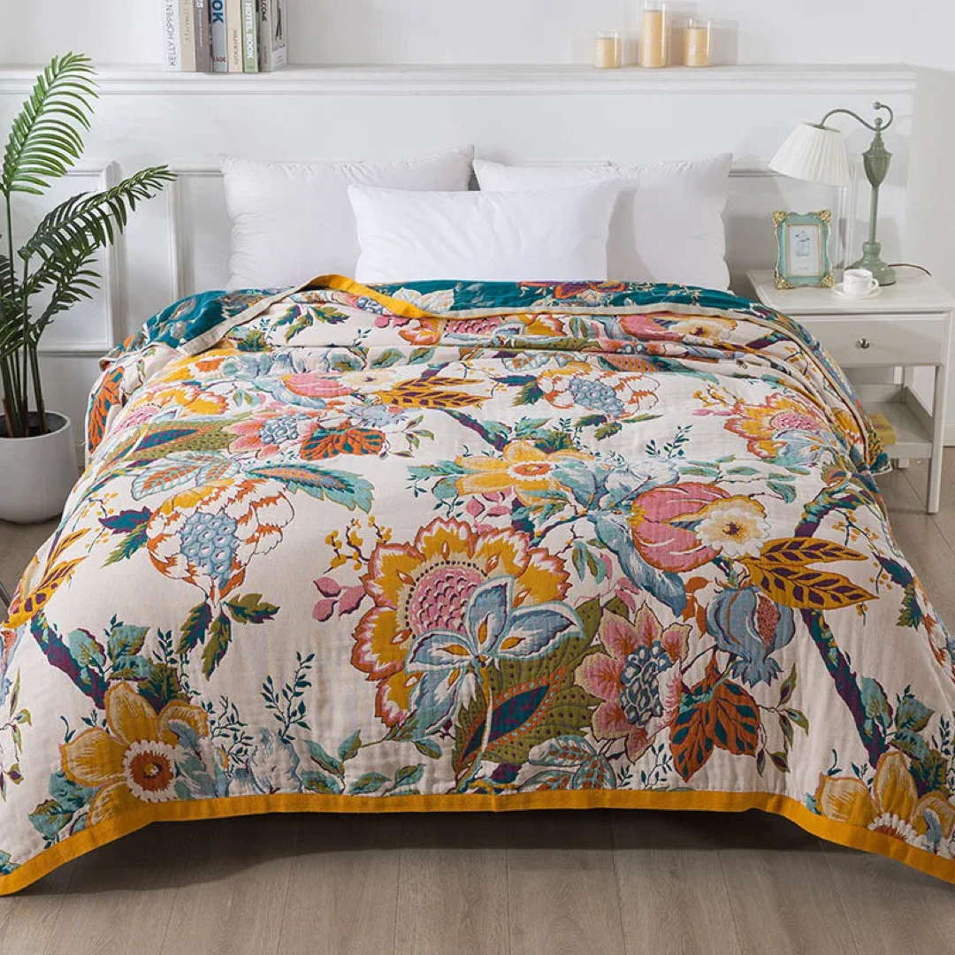 Multicolor floral cotton coverlet with pink, blue and yellow blooms spread over a bed