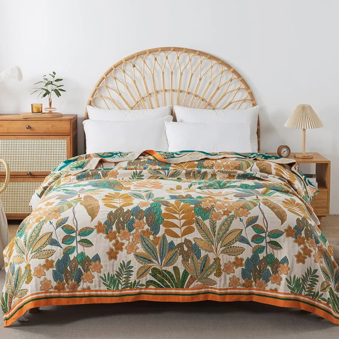 Cream cotton coverlet with caramel, orange and green leaves spread over a bed