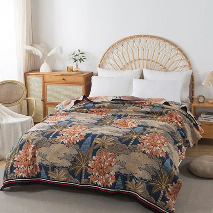 Navy floral cotton coverlet with coral trees and gold palms spread over a bed