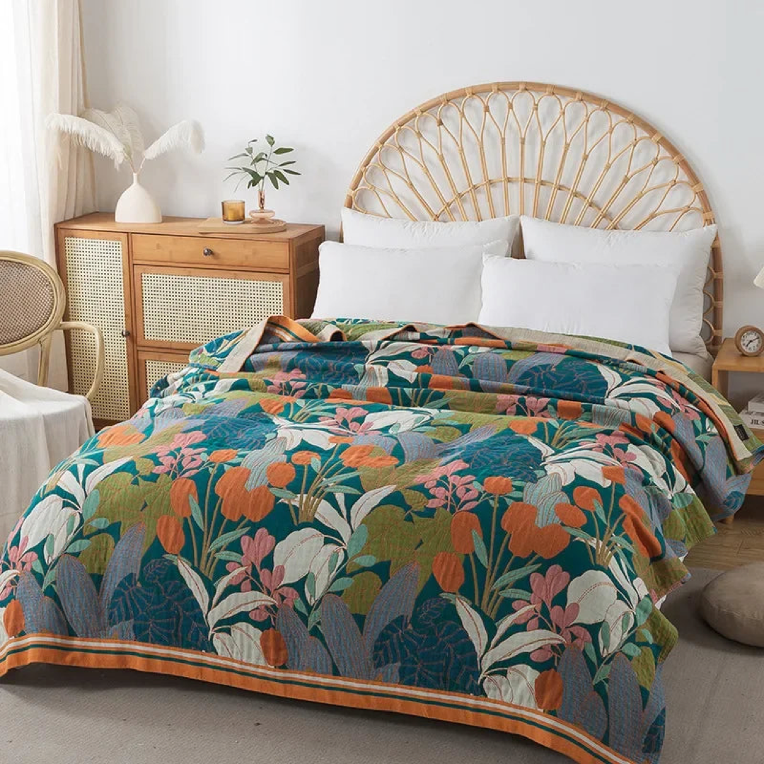 Teal and orange floral cotton coverlet spread over a bed with a rattan headboard, seen from the corner
