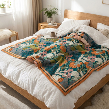 Teal and orange floral cotton coverlet laid over someone resting in a wooden bed as a light top layer