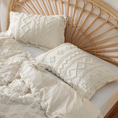 Close-up of beige tufted pillow shams with diamond and cross motifs against a rattan headboard