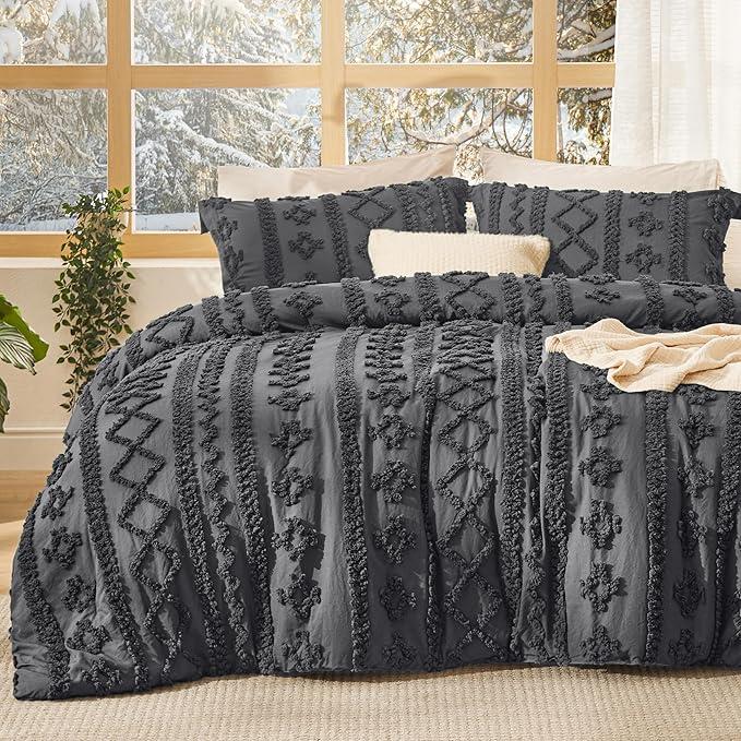 Dark gray tufted duvet cover set with matching shams on a bed in front of a snowy window