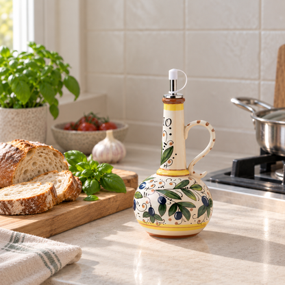Ceramic olive oil bottle with painted olive branches on a stone kitchen counter beside a bread board