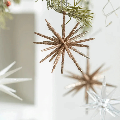 Champagne starburst and clear star ornaments hanging in front of white shelves