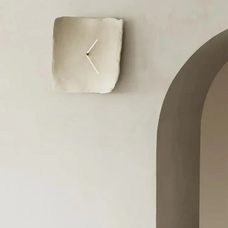 White crumpled resin wall clock on a plain wall beside an arched doorway