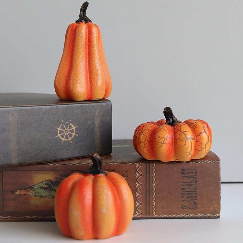 Three unlit pumpkin lights stepped on books against a plain wall