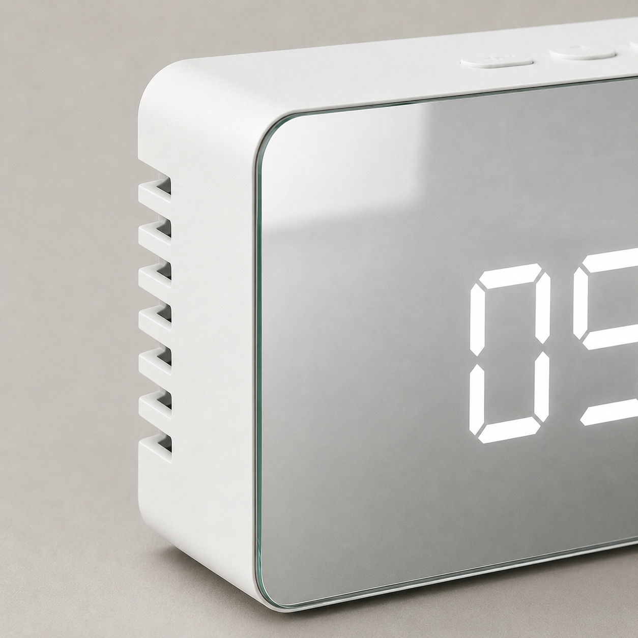Close view of the alarm clock's front corner, showing the angled slots cut into the white plastic shell