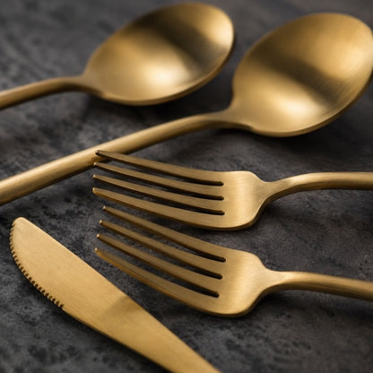 Close view of matte gold spoons, forks and serrated knife showing the brushed finish