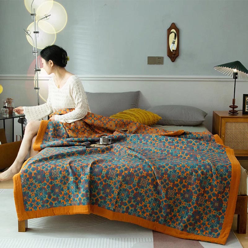 Orange and blue jacquard quilt spread over a bed with a wide orange border hanging at the foot