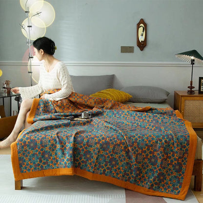 Orange and blue jacquard quilt spread over a bed with a wide orange border hanging at the foot
