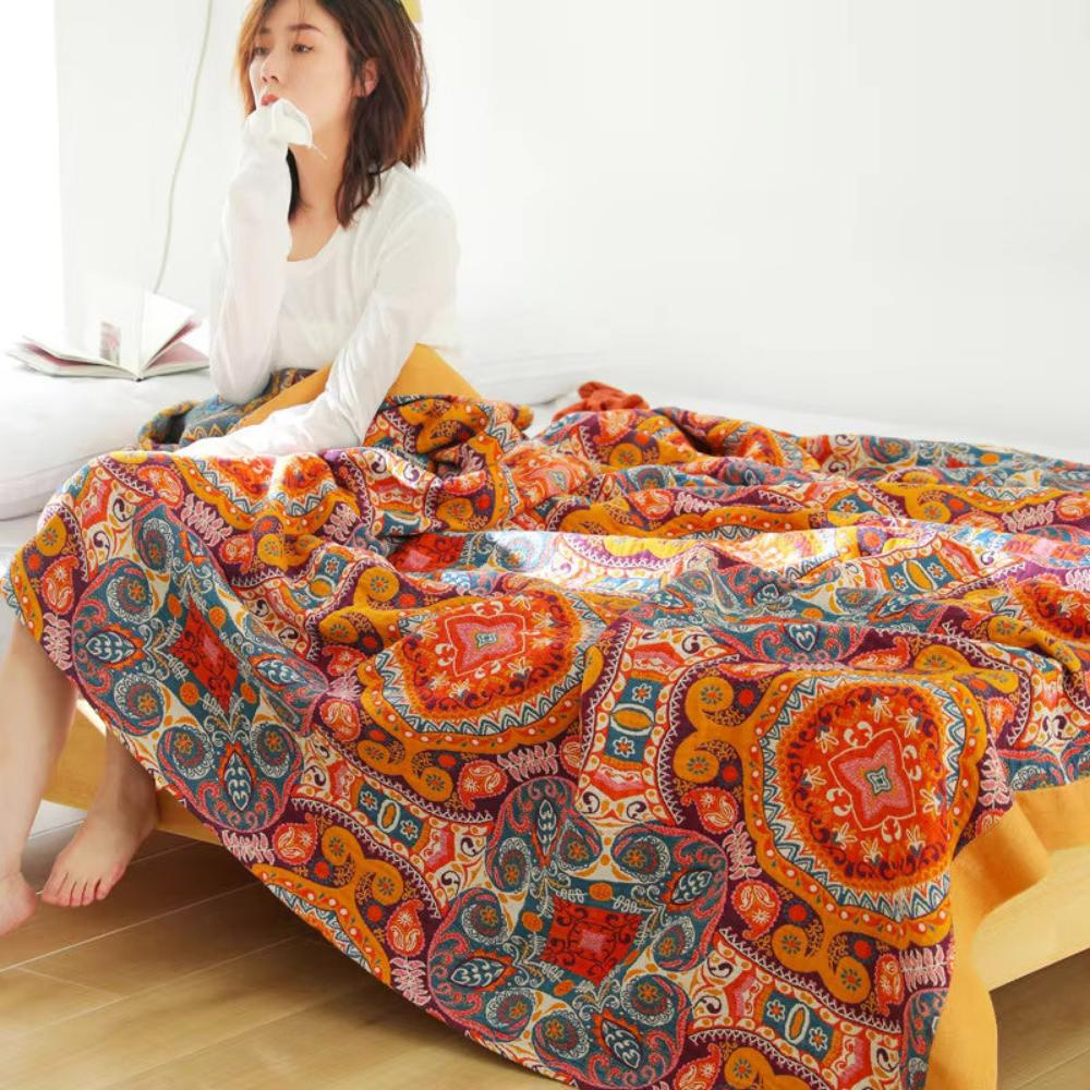 Person sitting on a bed with the medallion throw blanket over their legs