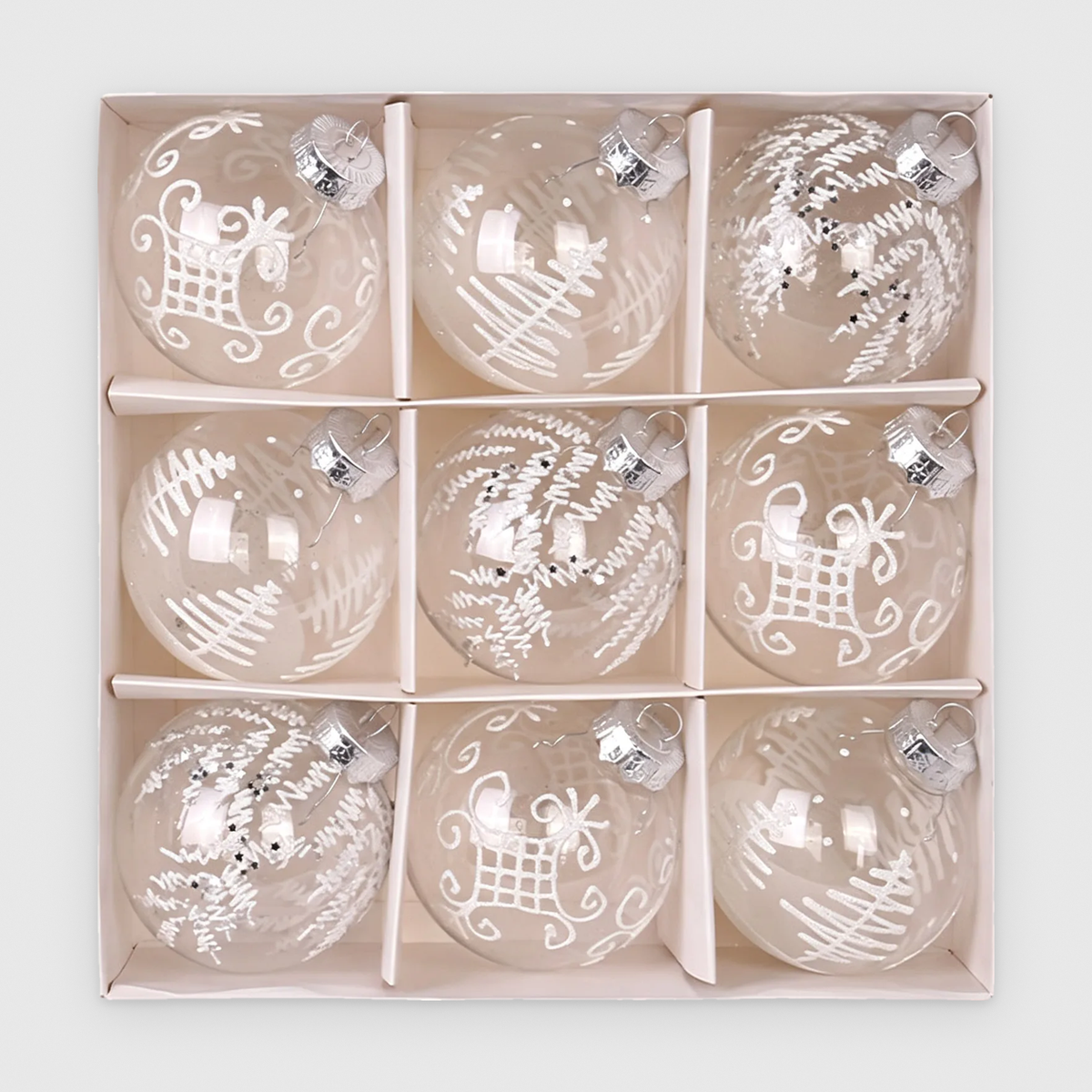 Box of 9 clear Christmas baubles with white glitter sleigh, tree and frond designs and silver caps