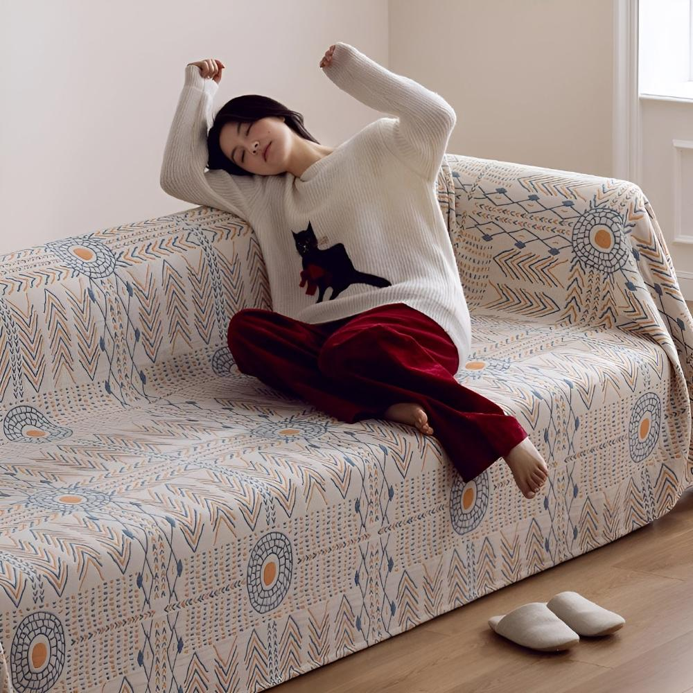 Person stretching on a sofa covered with the cream sun and chevron cotton blanket