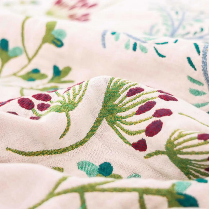 Close-up of burgundy seed heads and green stems woven into the cream cotton gauze