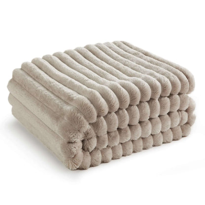 Beige pleated faux rabbit fur throw folded in a neat stack on a white background