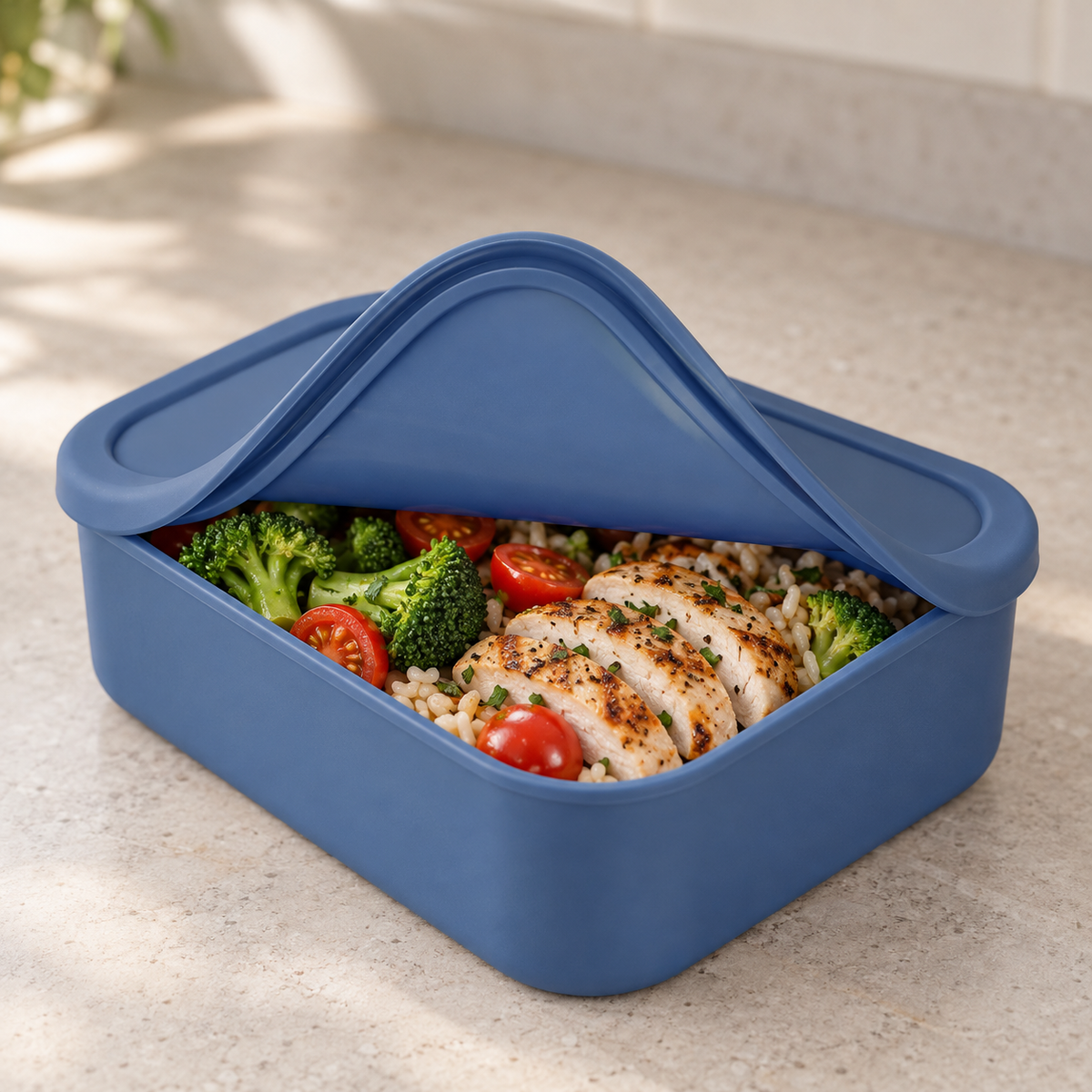 Close-up of a blue silicone container with its soft lid peeled back from one corner over rice and chicken