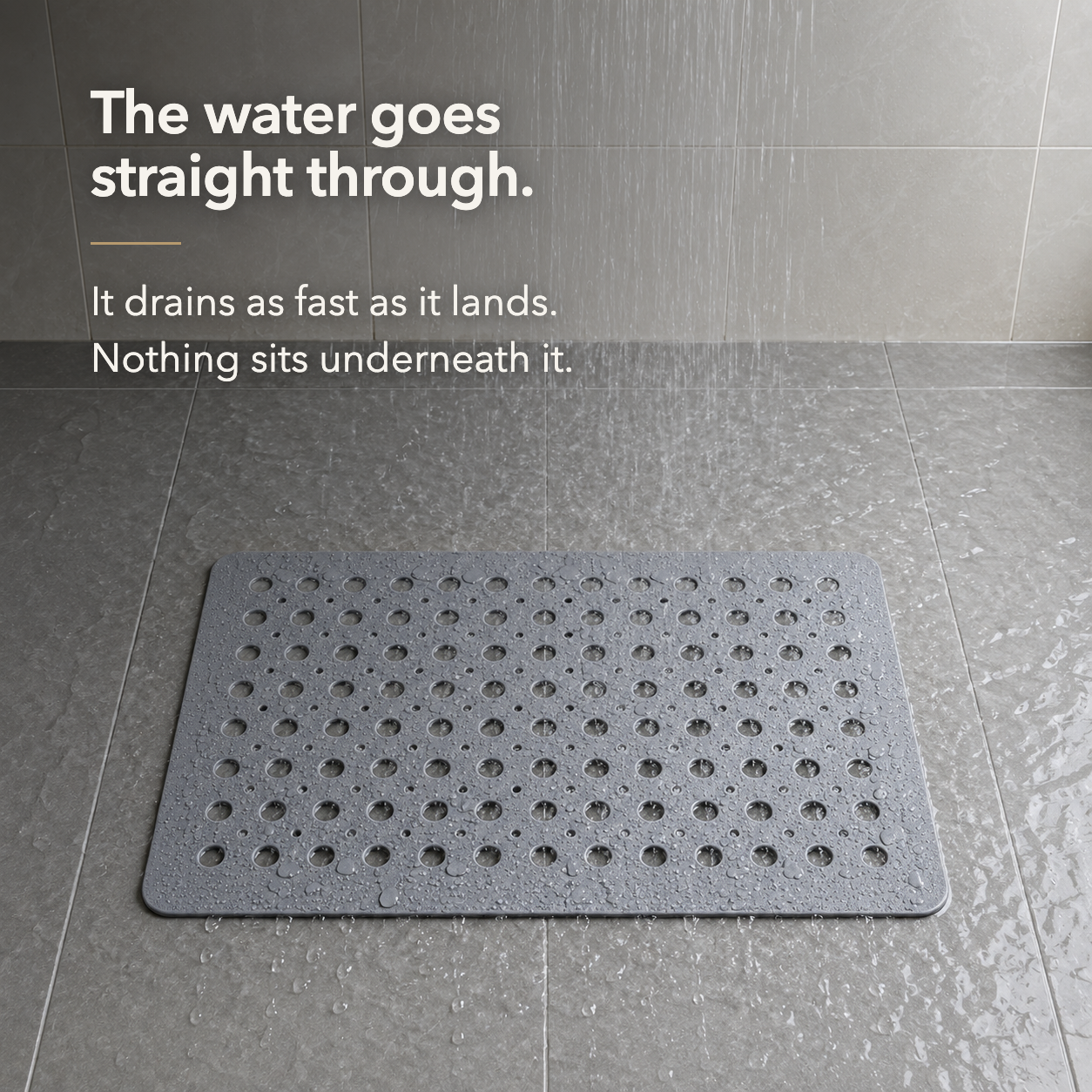 Water falling on a gray shower mat and draining straight through its holes with no pooling