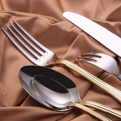 Close view of the serrated dinner knife, dinner fork, cake fork and spoons with gold trim